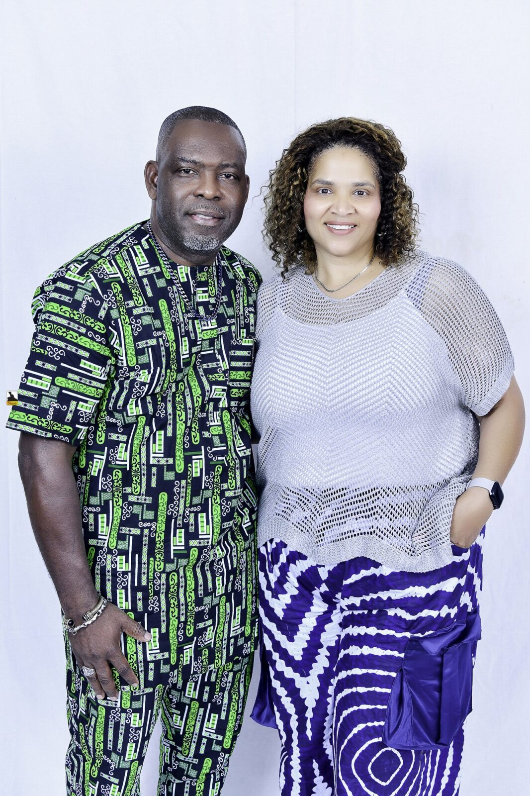 Man in green patterned clothing and woman in a light top posing together
