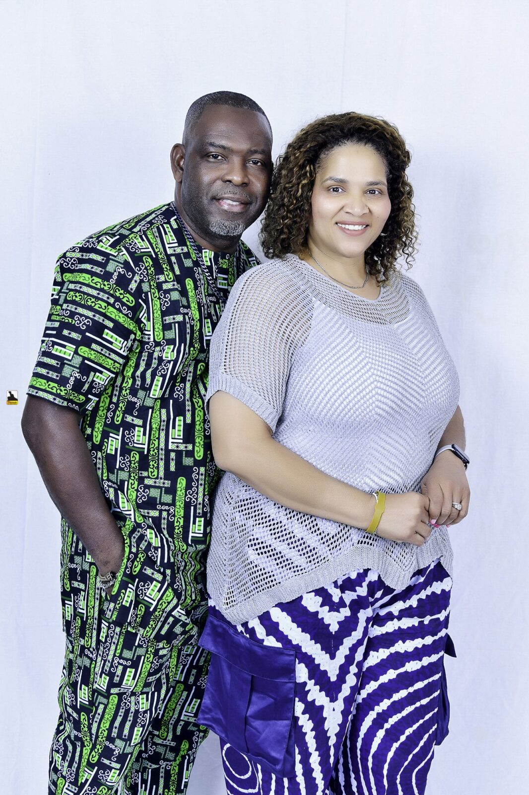 Man in green patterned clothing and woman in a light top posing together