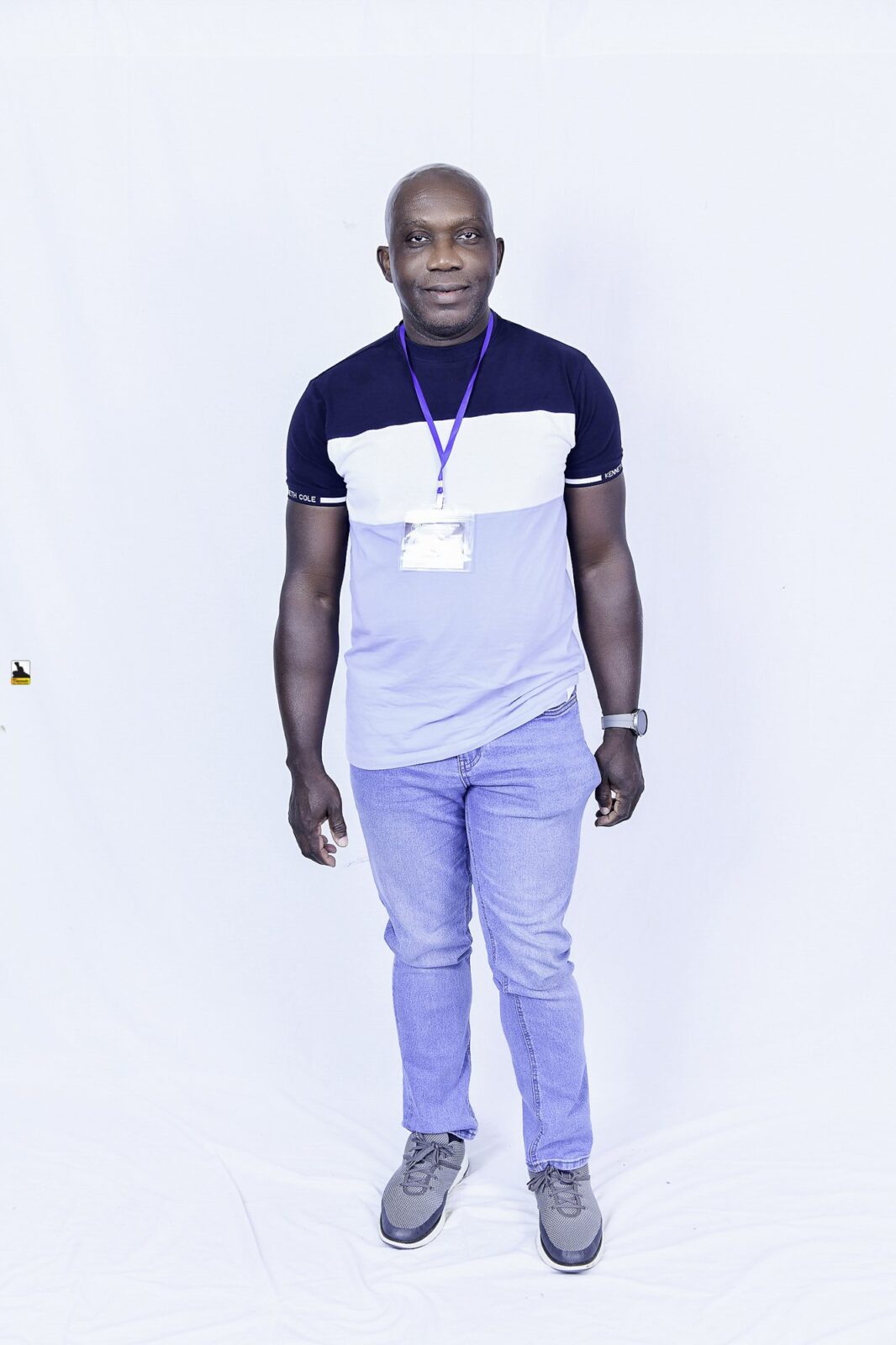 Man in a two-tone T-shirt and light trousers posing against a white backdrop