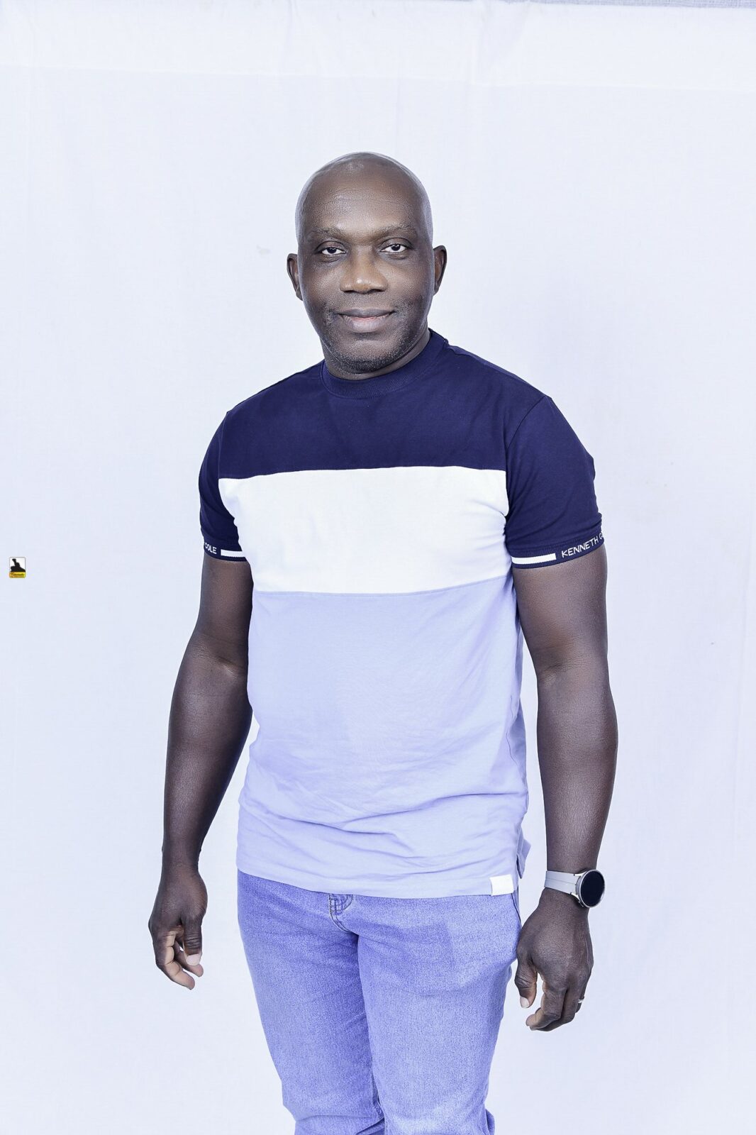 Man in a two-tone T-shirt and light trousers posing against a white backdrop
