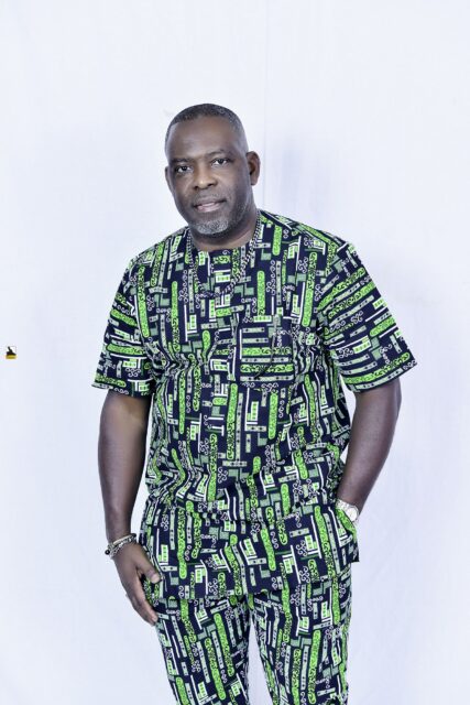Man in a green patterned outfit posing against a white backdrop