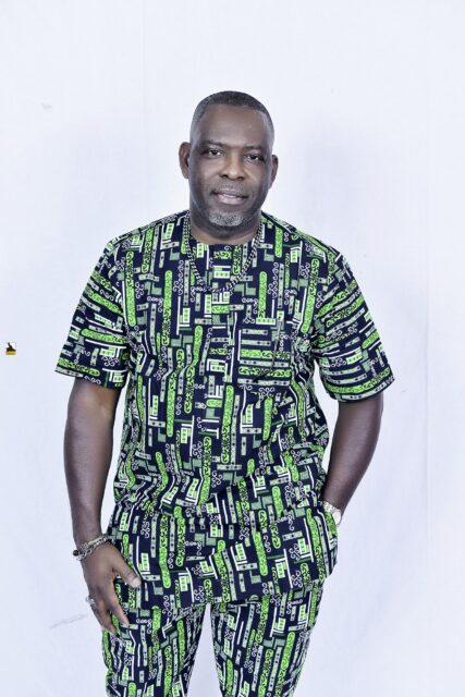 Man in a green patterned outfit posing against a white backdrop