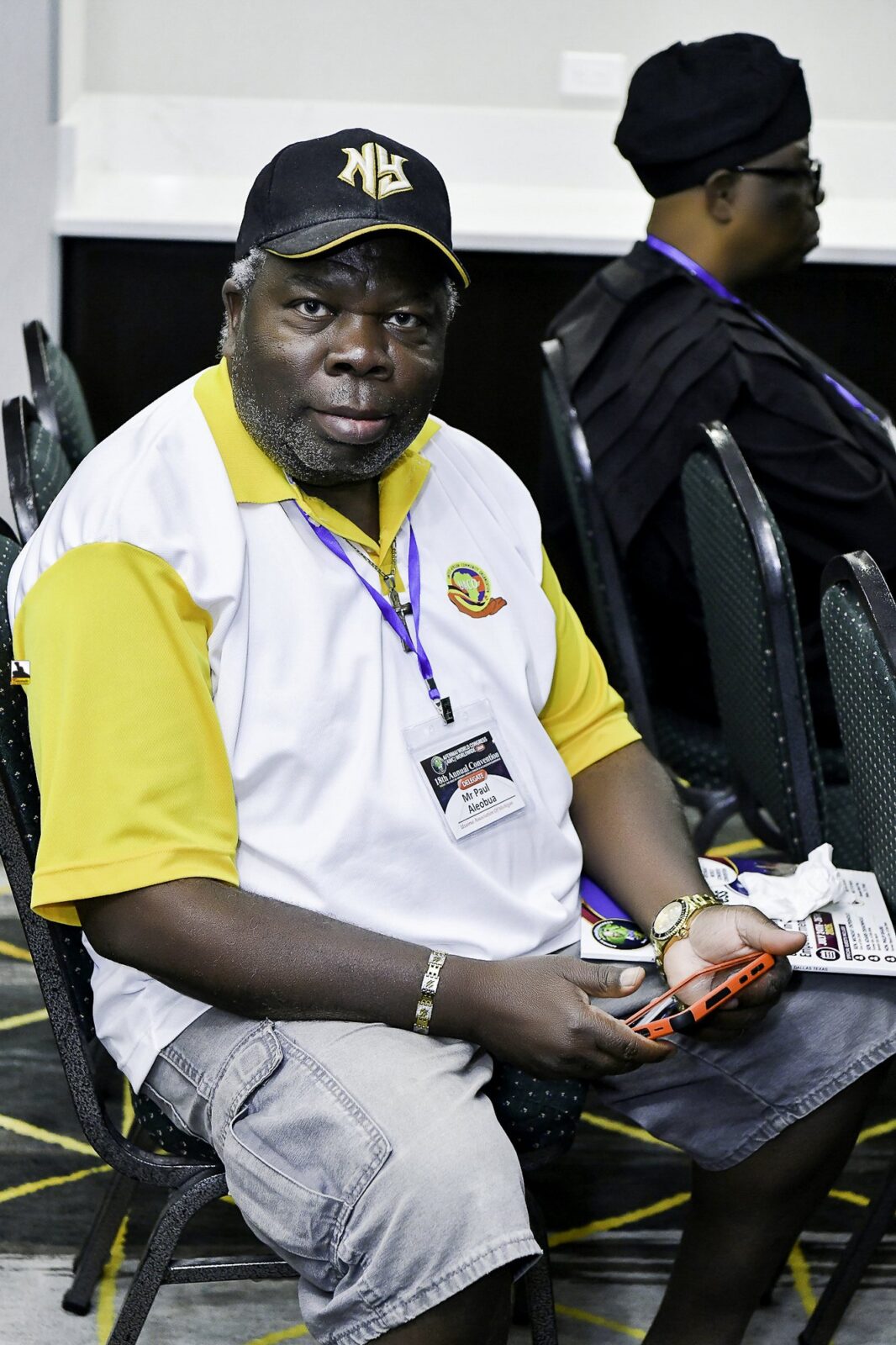 Man in a white and yellow polo shirt seated in the room