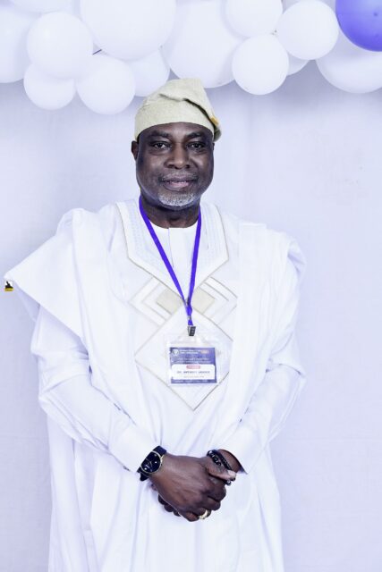 Man in embroidered white clothing and a pale cap by the balloons