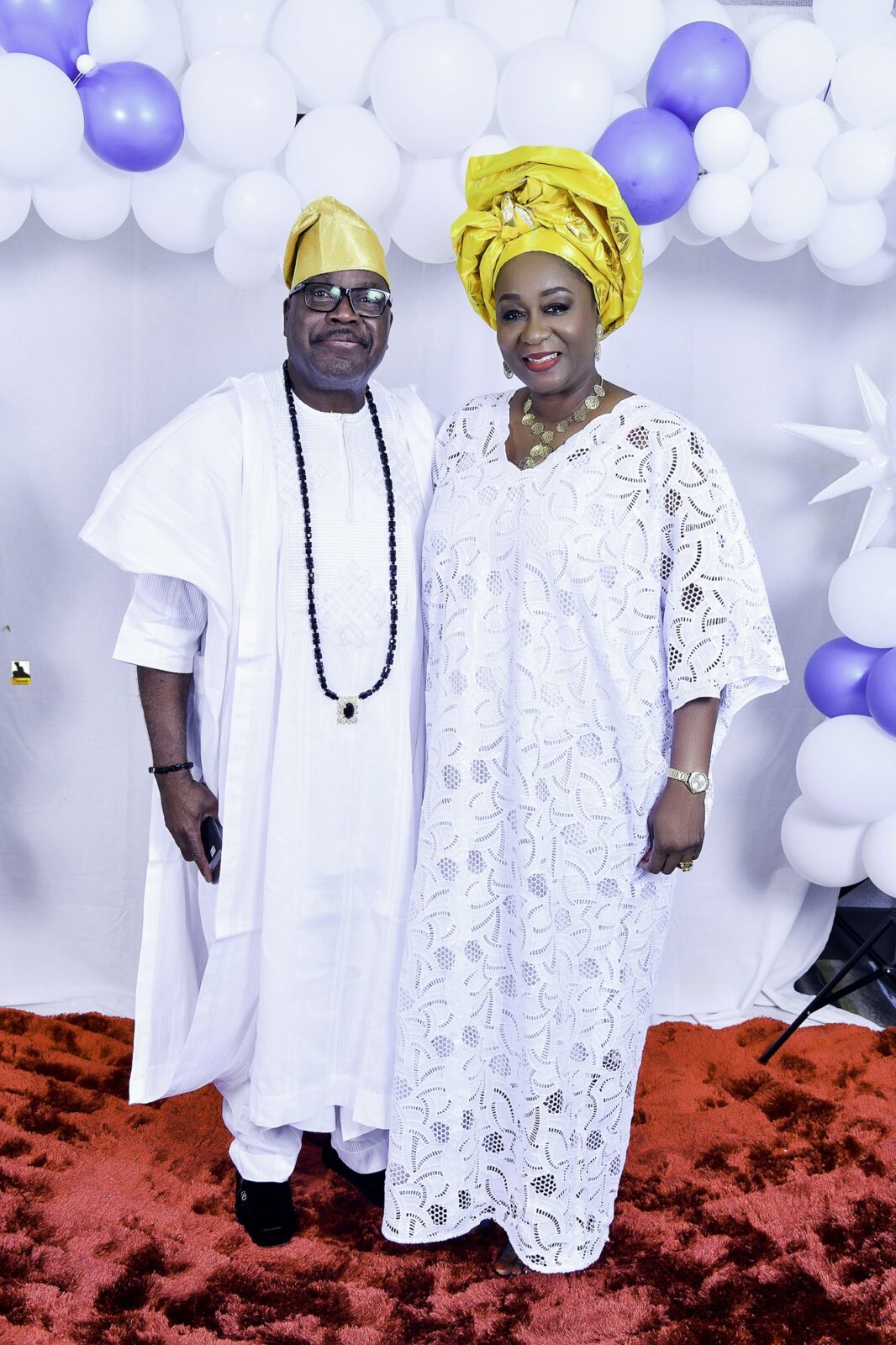 Two attendees in white clothing, one wearing a yellow headwrap