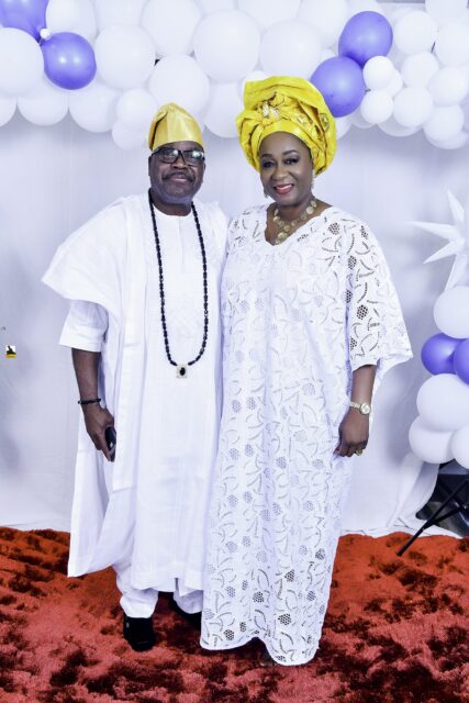 Two attendees in white clothing, one wearing a yellow headwrap