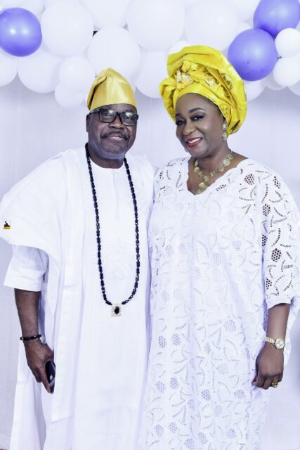 Two attendees in white clothing, one wearing a yellow headwrap