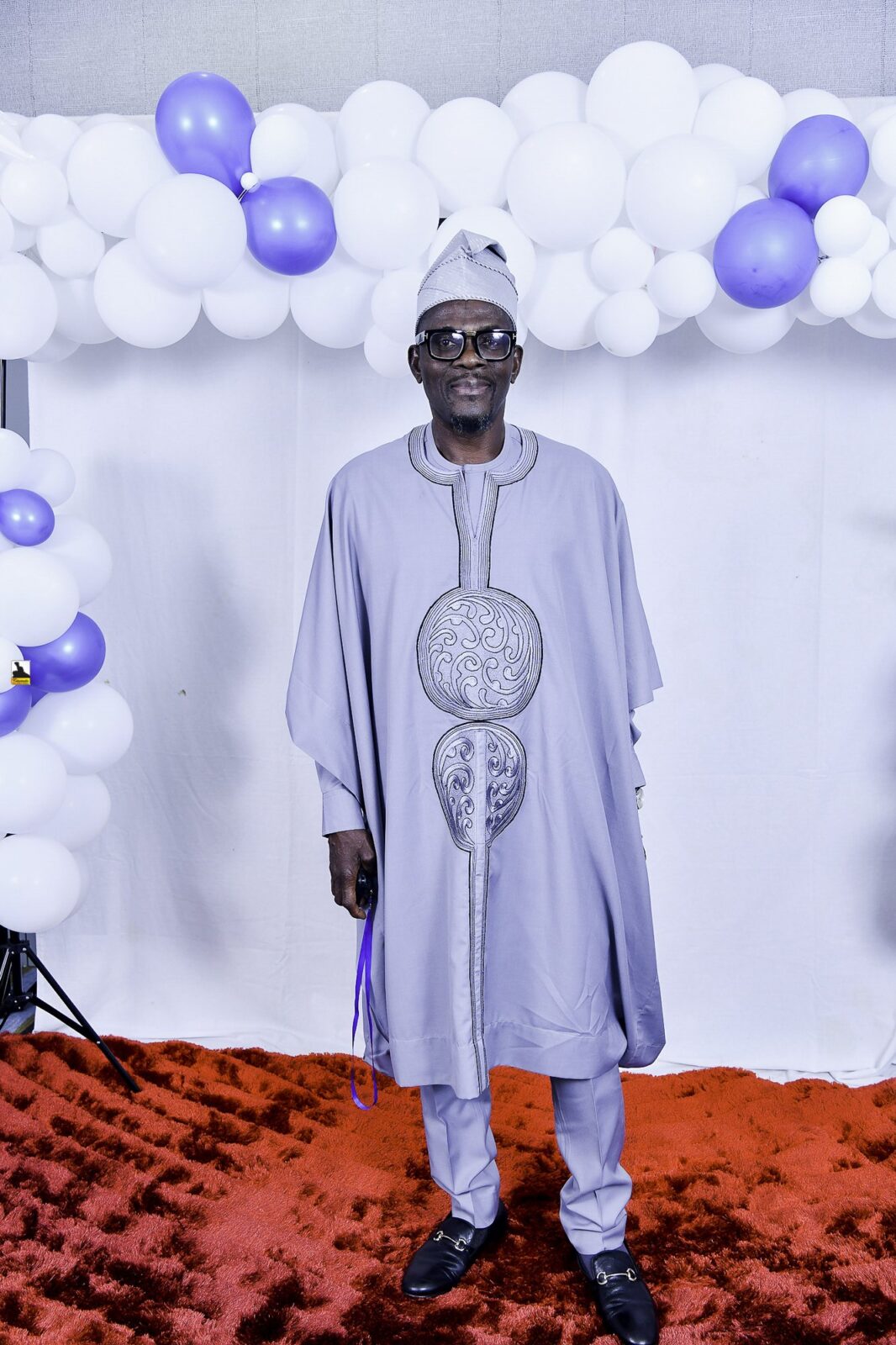 Man in gray embroidered clothing posing beside the balloons