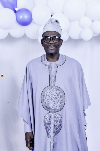 Man in gray embroidered clothing posing beside the balloons