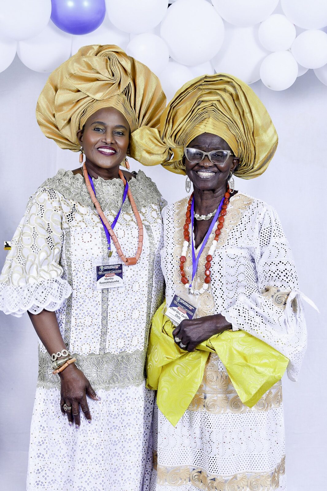 Two women in white lace and gold headwraps standing together