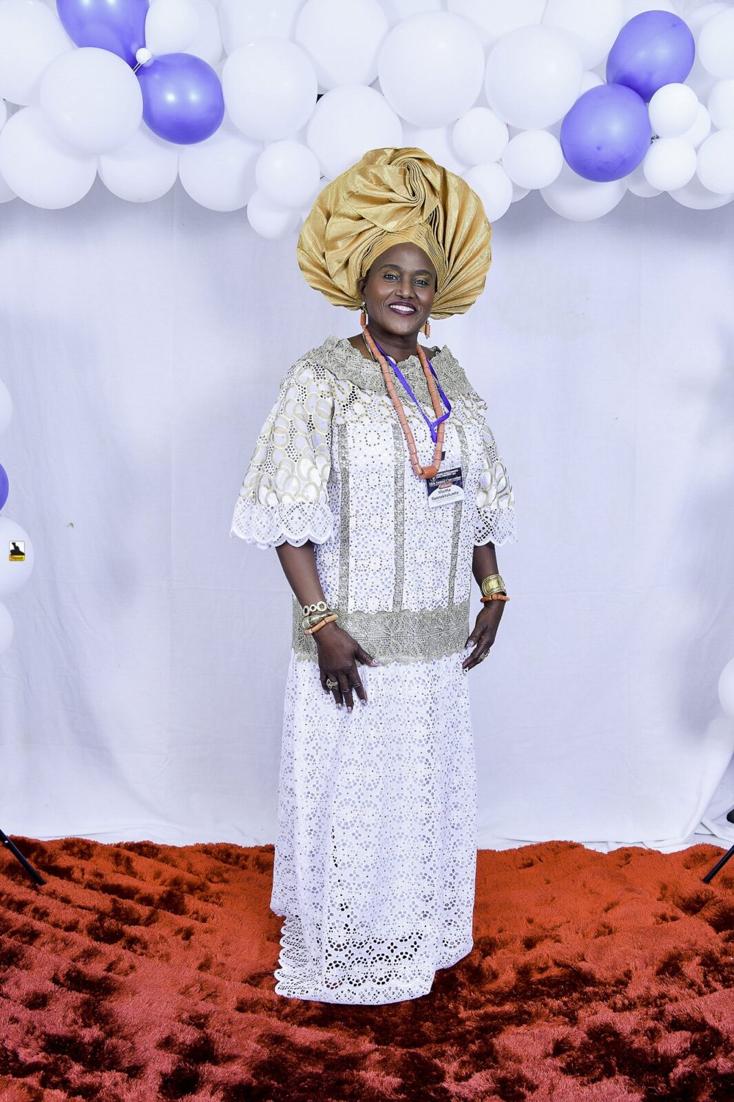 Woman in white lace and a gold headwrap posing by the balloons