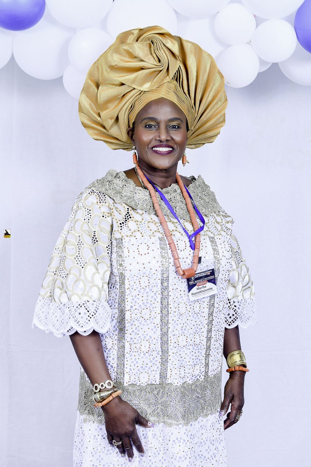 Woman in white lace and a gold headwrap posing by the balloons