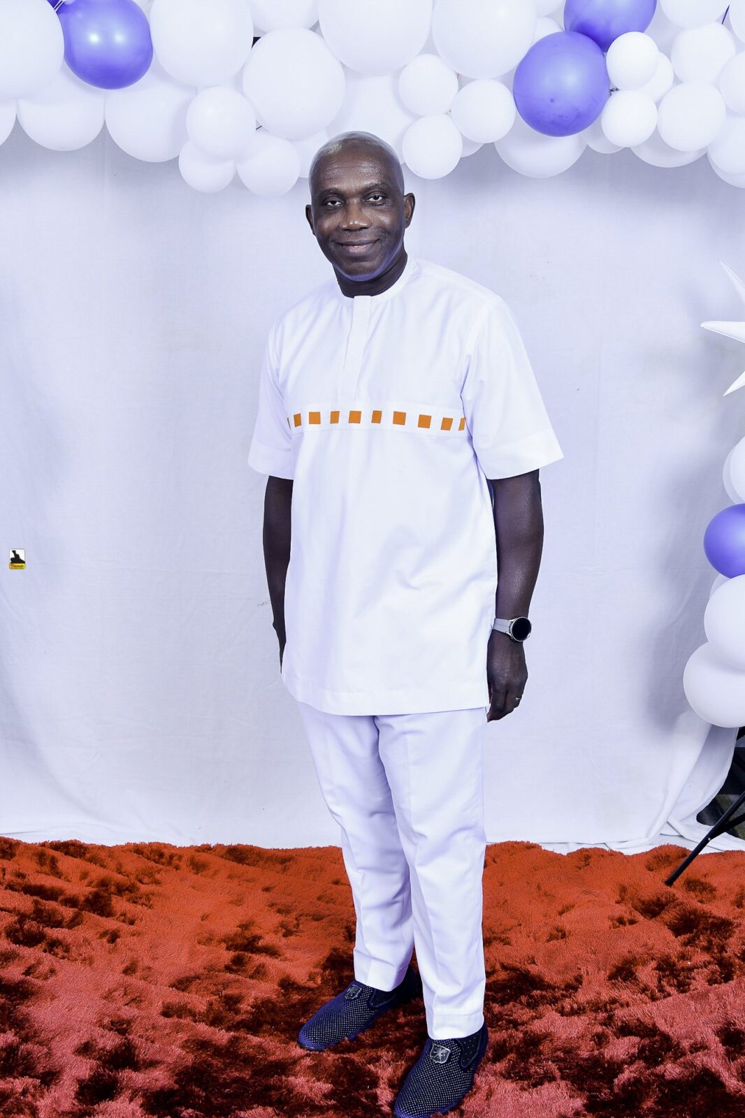 Man in a white outfit with orange detailing by the balloons