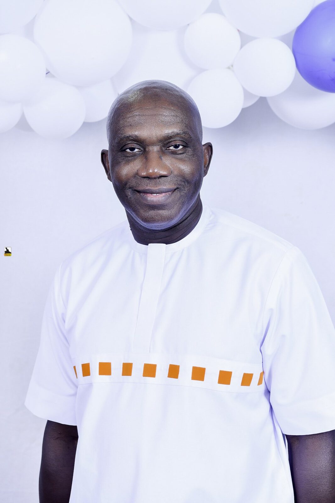 Man in a white outfit with orange detailing by the balloons