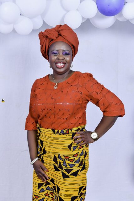 Woman in an orange top and headwrap with a yellow patterned wrapper