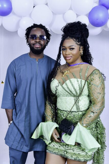 Man in blue clothing and woman in a green dress posing together