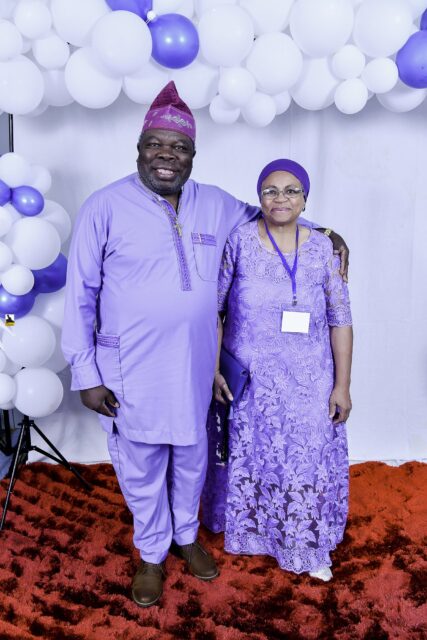 Two attendees in lavender clothing standing together by the balloons