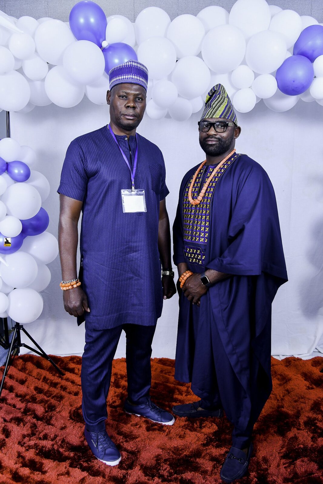 Two men in dark blue clothing and caps posing together