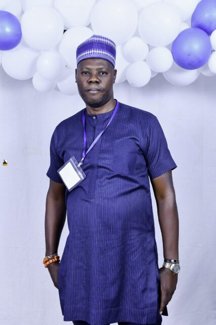 Man in a blue shirt and cap posing by the balloons