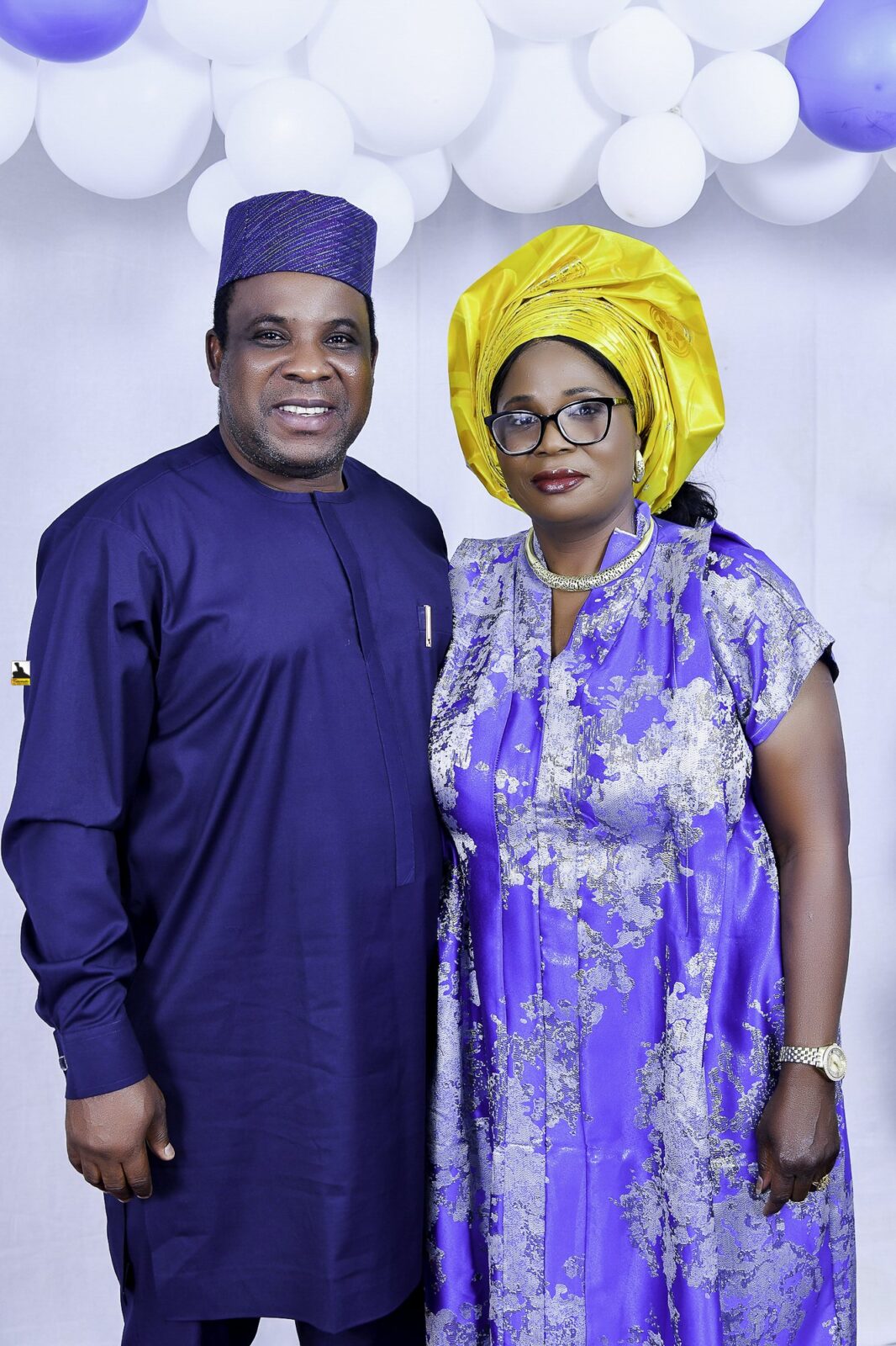 Man in blue and woman in a blue patterned outfit with a yellow headwrap