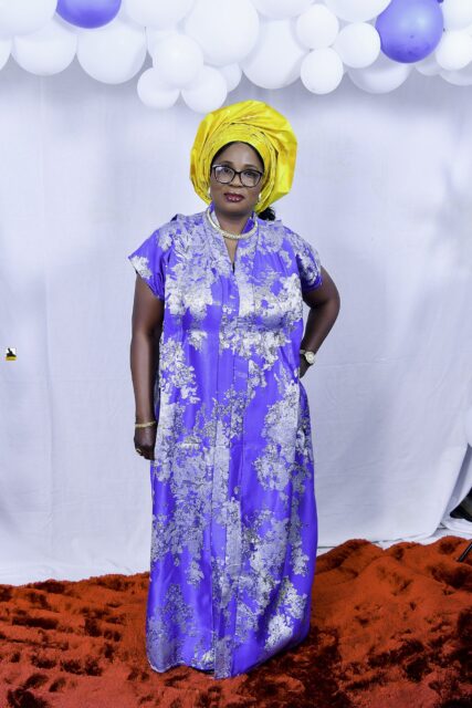 Woman in a blue patterned outfit and yellow headwrap by the balloons