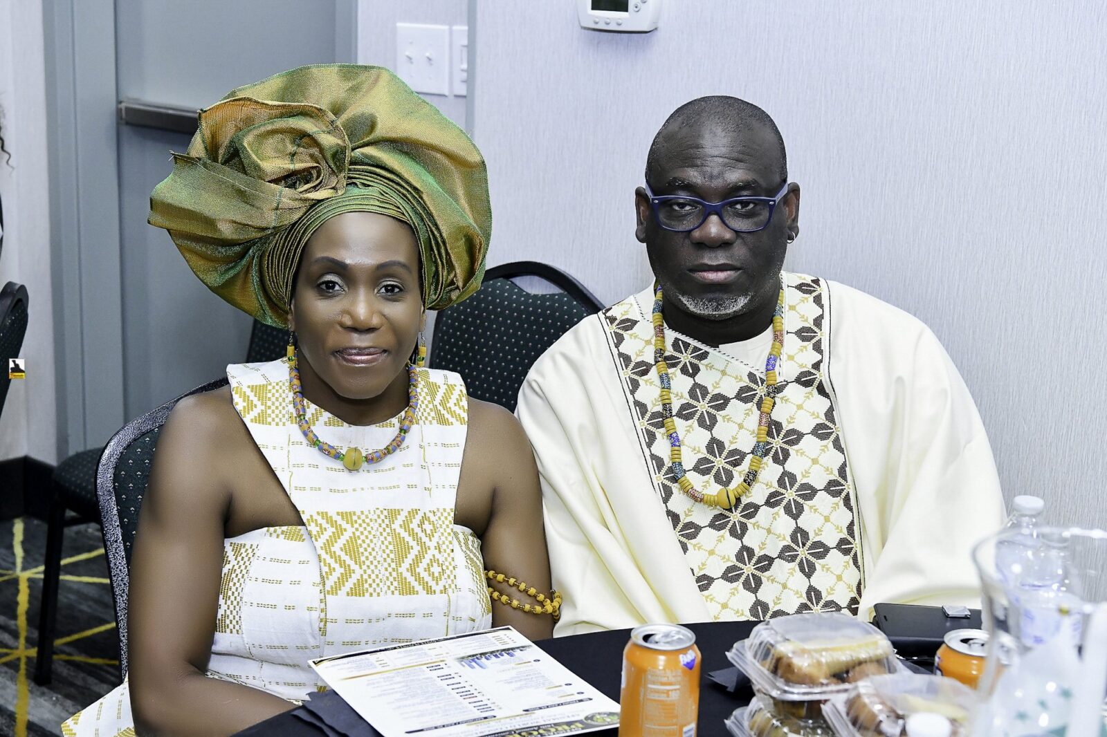 Two attendees in cream clothing seated together at a table