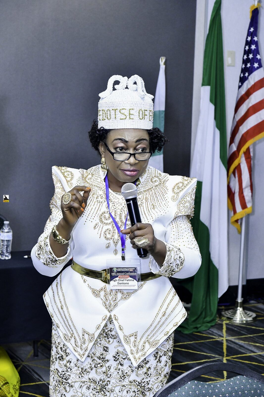 Woman in white and gold clothing speaking into a microphone