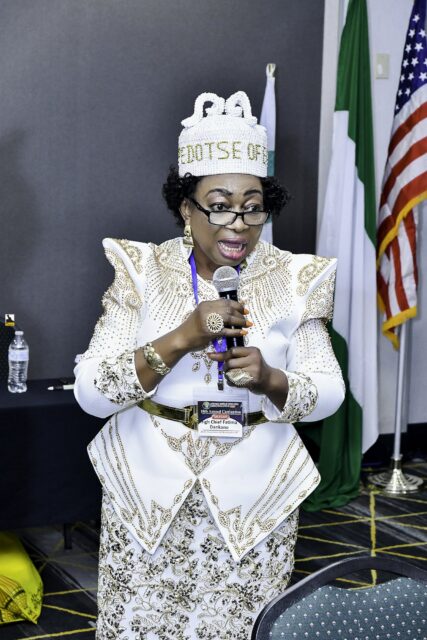 Woman in white and gold clothing speaking into a microphone