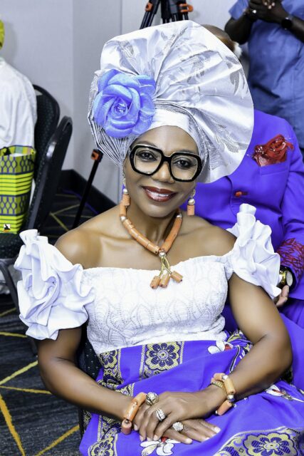 Smiling woman in a silver headwrap and glasses seated in the room