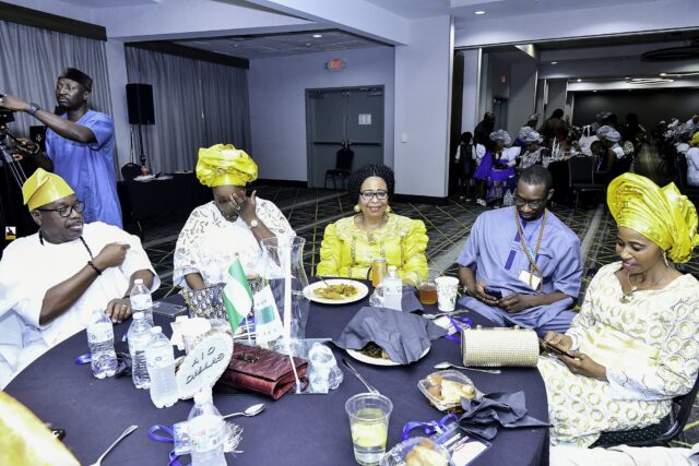 Attendees wearing yellow headwraps and caps seated around a table