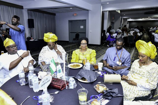 Attendees wearing yellow headwraps and caps seated around a table