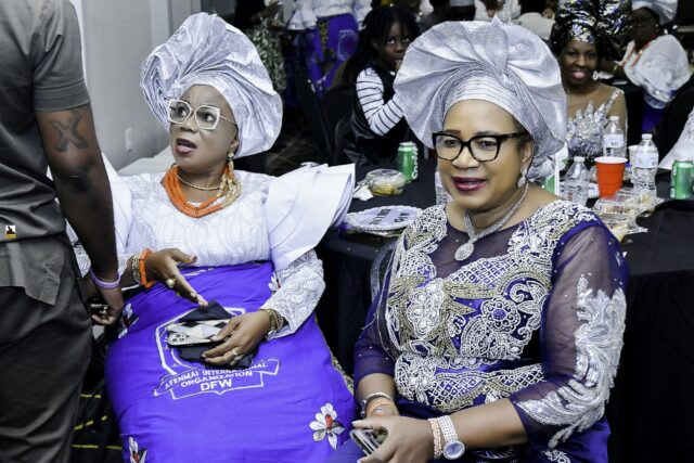Two women in silver headwraps seated side by side