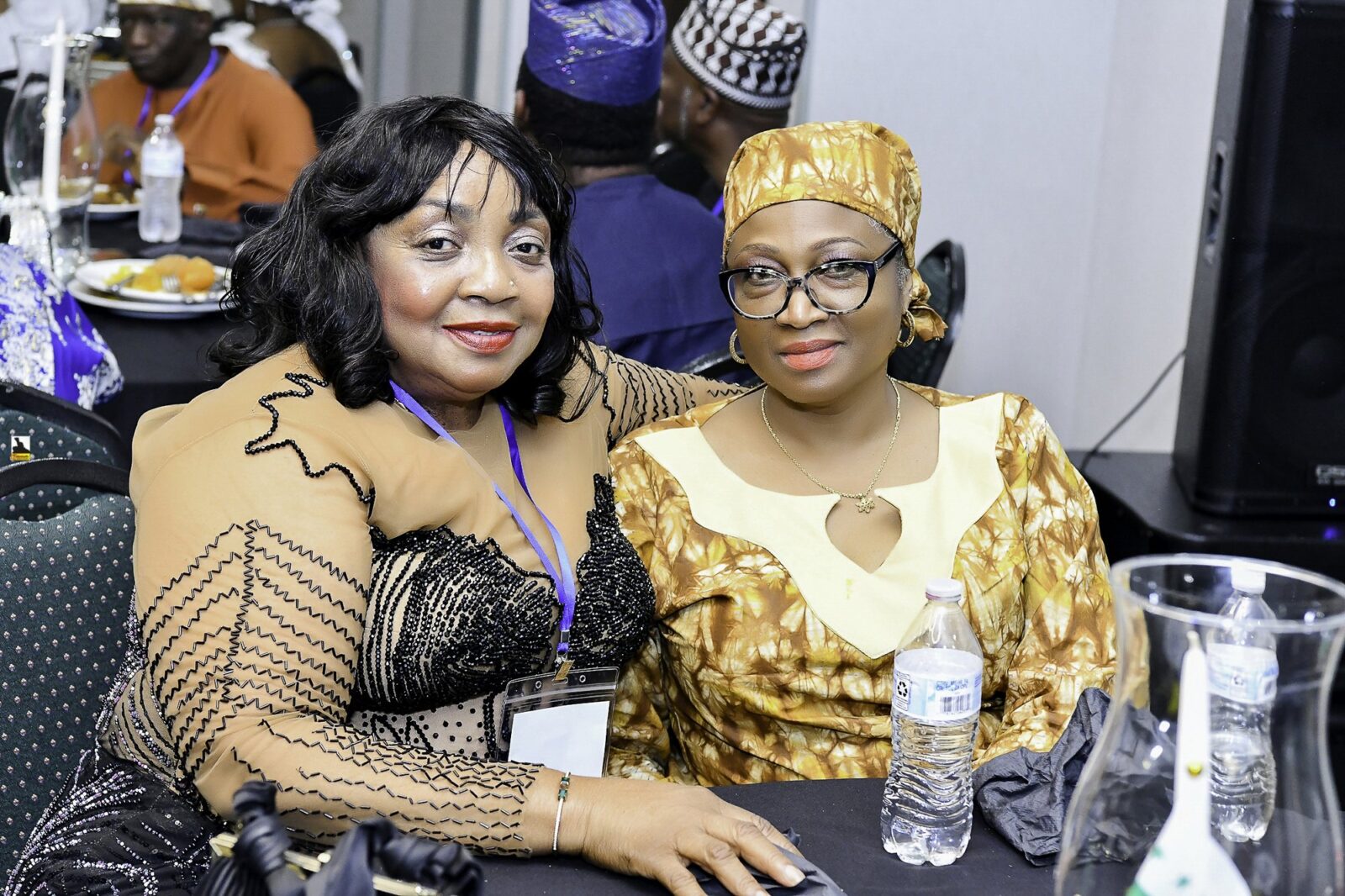 Two women in black and gold clothing seated together