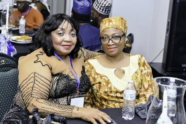 Two women in black and gold clothing seated together