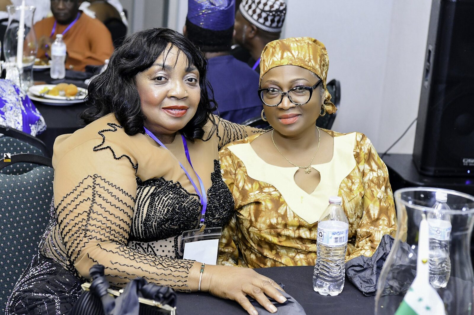 Two women in black and gold clothing seated together