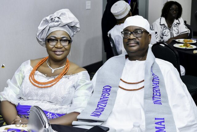 Two attendees in white clothing and silver headwear seated together