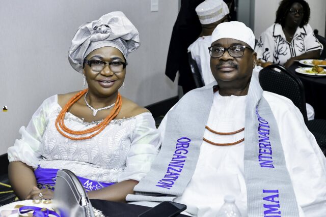 Two attendees in white clothing and silver headwear seated together
