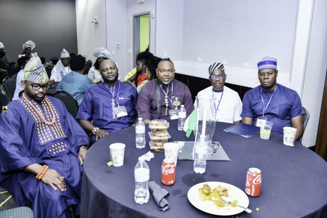 Five men in blue and white clothing seated around a table
