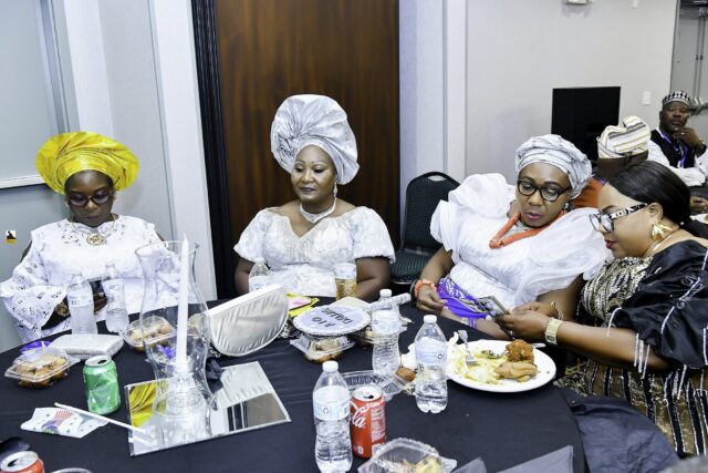 Women in white clothing and bright headwraps seated at a table
