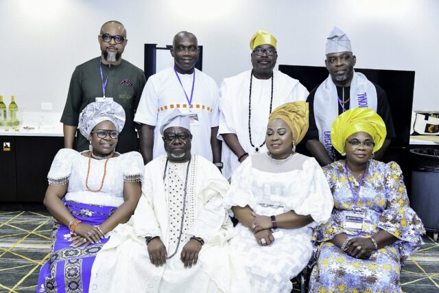 Eight attendees in white, blue and green clothing posing in two rows