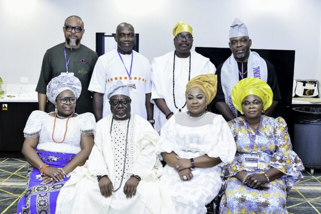 Eight attendees in white, blue and green clothing posing in two rows