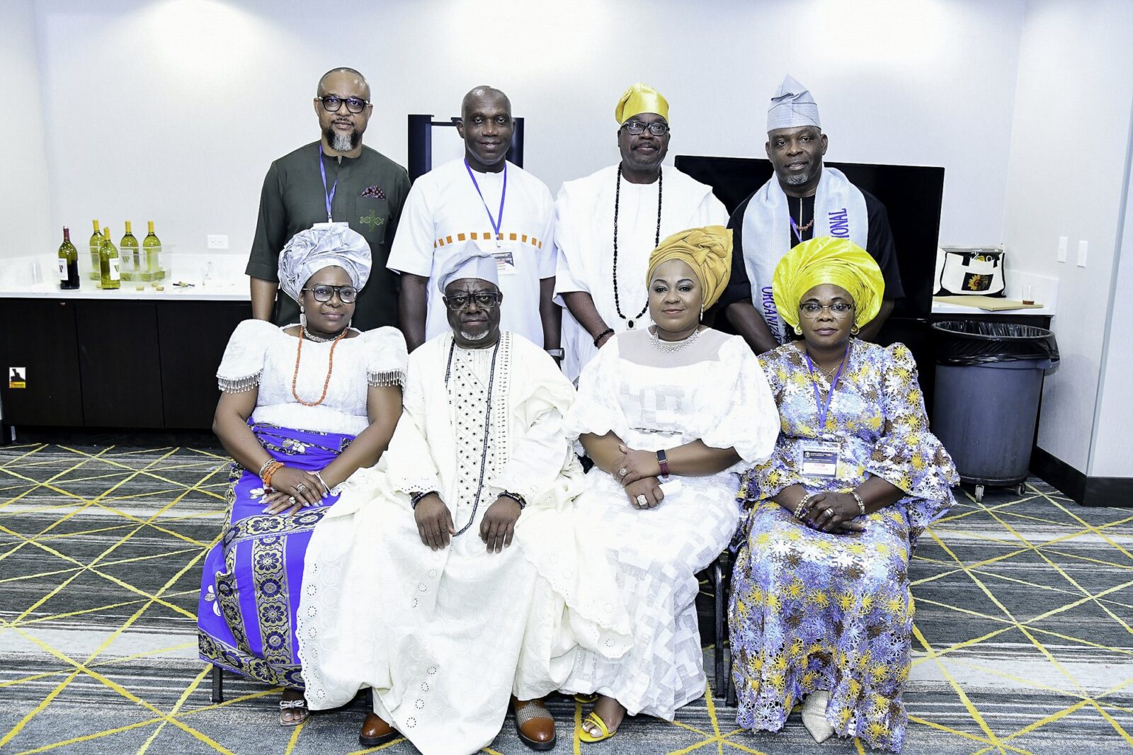 Eight attendees in white, blue and green clothing posing in two rows