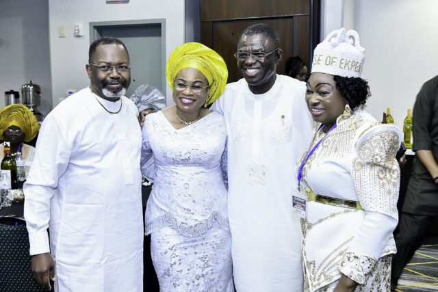 Four smiling attendees standing together in white clothing and bright headwear